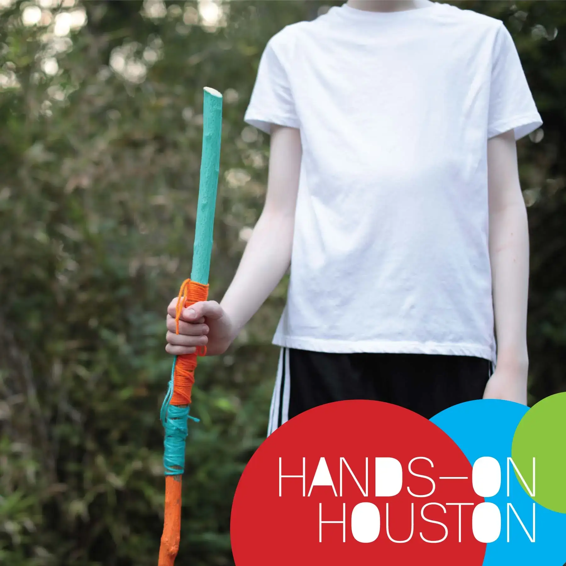 Hands-on Houston walking stick activity. Photo of a boy holding a painted and yarn wrapped walking stick in the craft garden.